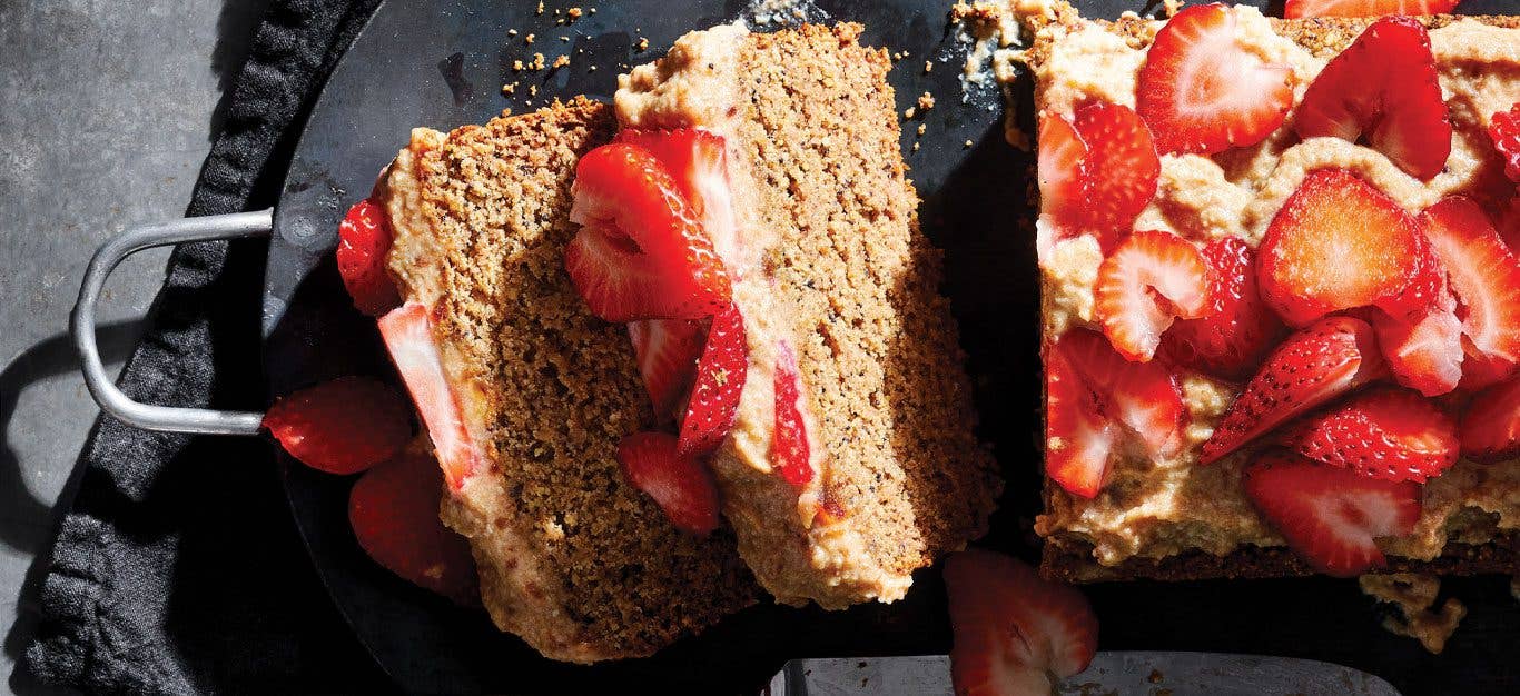 Almond Poppy Seed Cake topped with strawberries on a slate serving tray