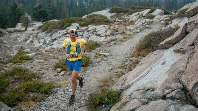 Austin Meyer running on a trail surrounded by boulders and trees