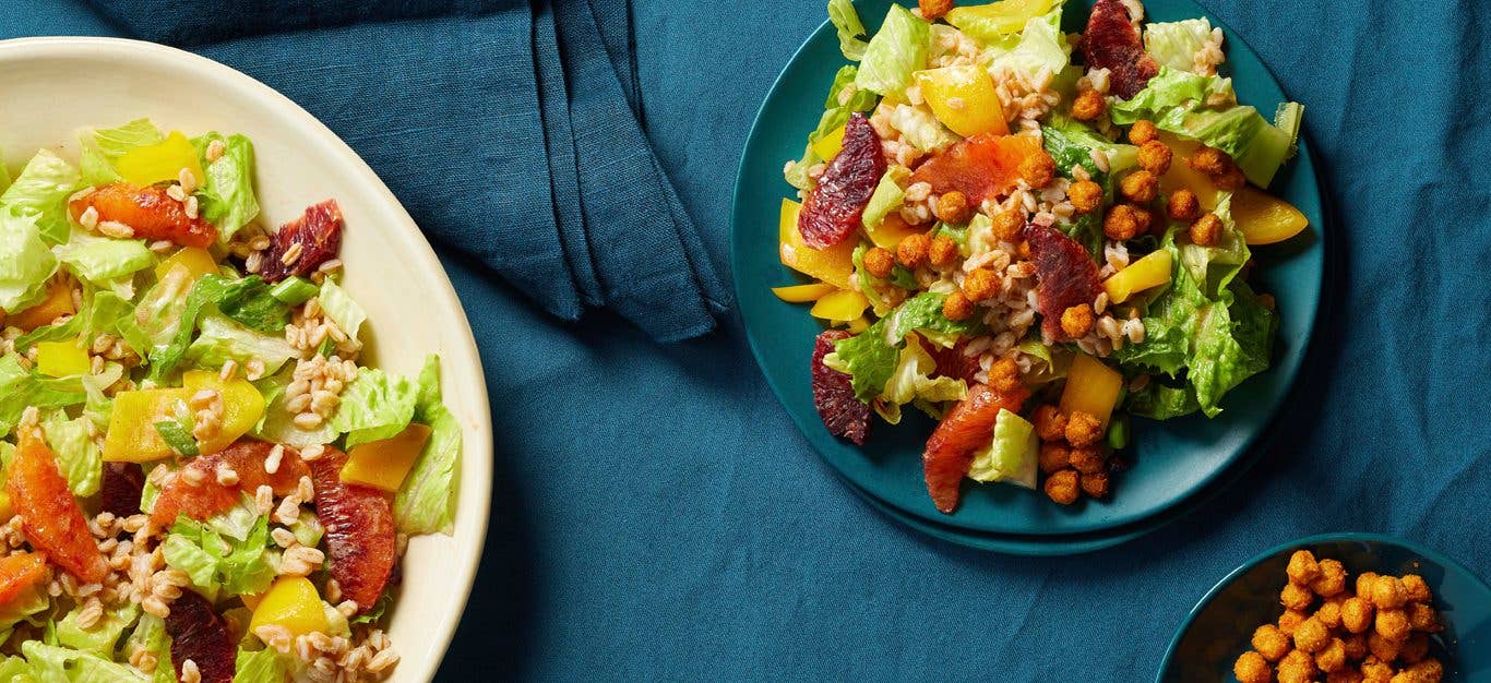 Blood Orange-Farro Salad with Crispy Chickpeas on a blue plate with a larger bowl of salad in a white dish