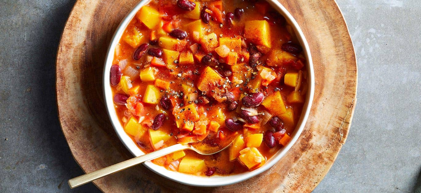 Butternut Squash and Red Bean Stew in a white bowl on a wooden serving plate