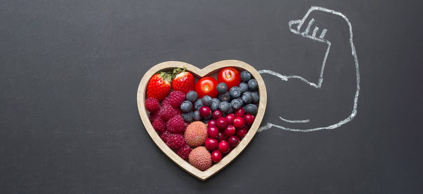 Bowl of fruit sitting atop chalkboard background, with a flexing arm drawn in chalk extending from the bowl of fruit