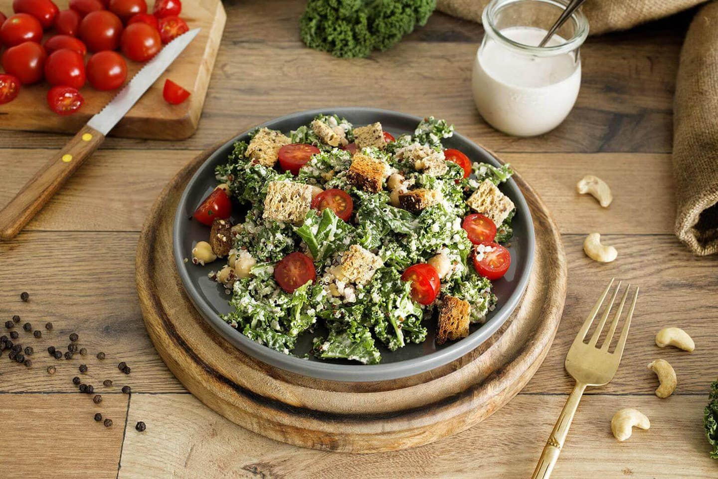 Vegan Kale Caesar Salad in a wooden bowl topped with croutons and tomatoes