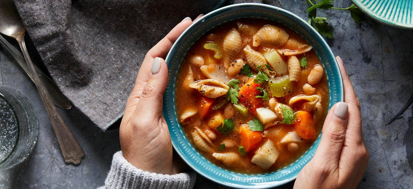 Harvest Vegetable Instant Pot Minestrone in a blue bowl being held in a woman's hands