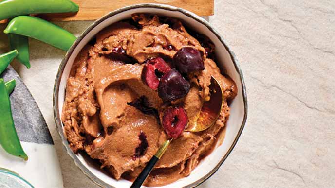 Chocolate Cherry Nice Cream in a white ceramic bowl with a gold metal spoon