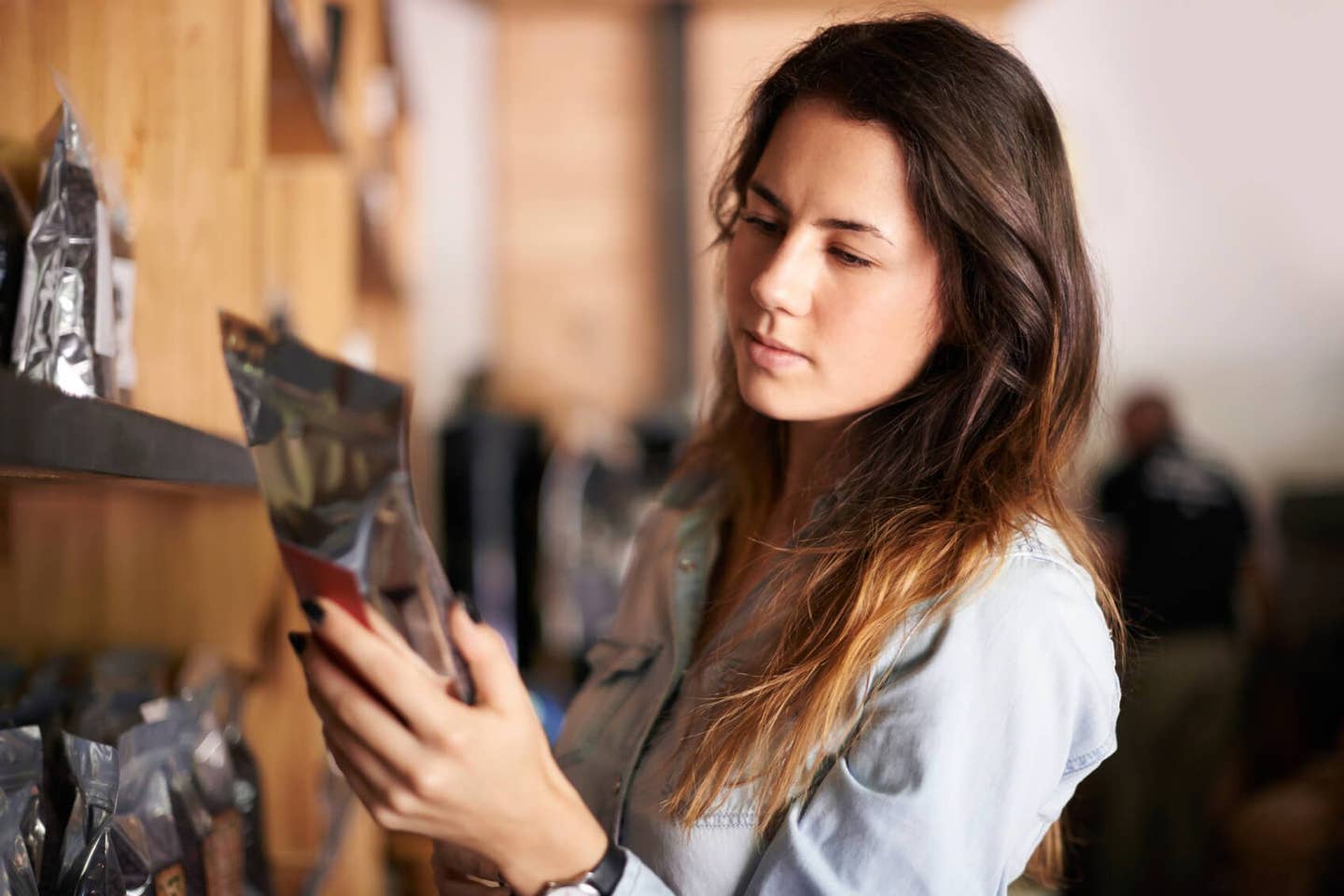 A woman examines the back of a package of food, studying the nutrition facts label