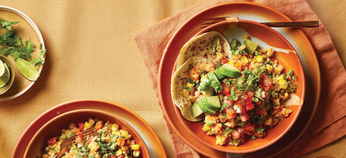 Quinoa Taco Bowls in orange ceramic bowls against a light orange fabric tablecloth