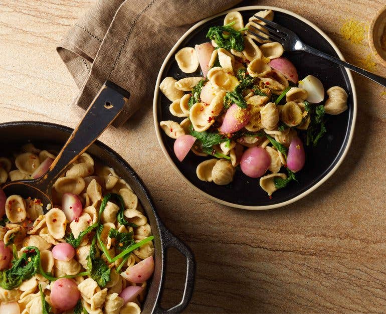 root to leaf radish pasta in white bowls on a wood table